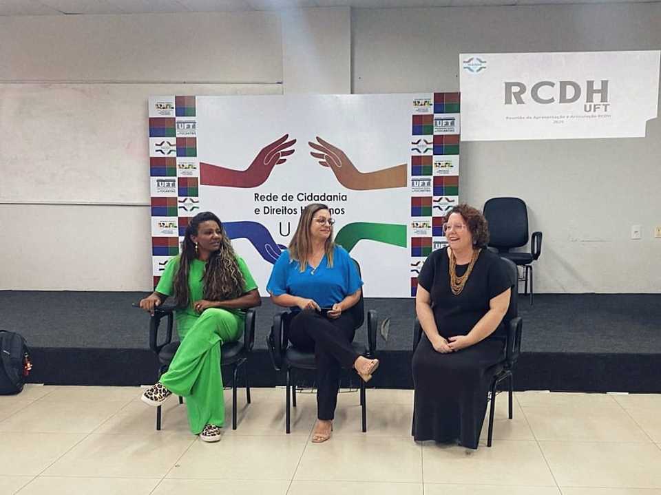 Uma mulher negra, Maria Santana, que é pró-reitora da UFT e outras duas mulheres brancas compõem mesa de discussão em uma sala de aula